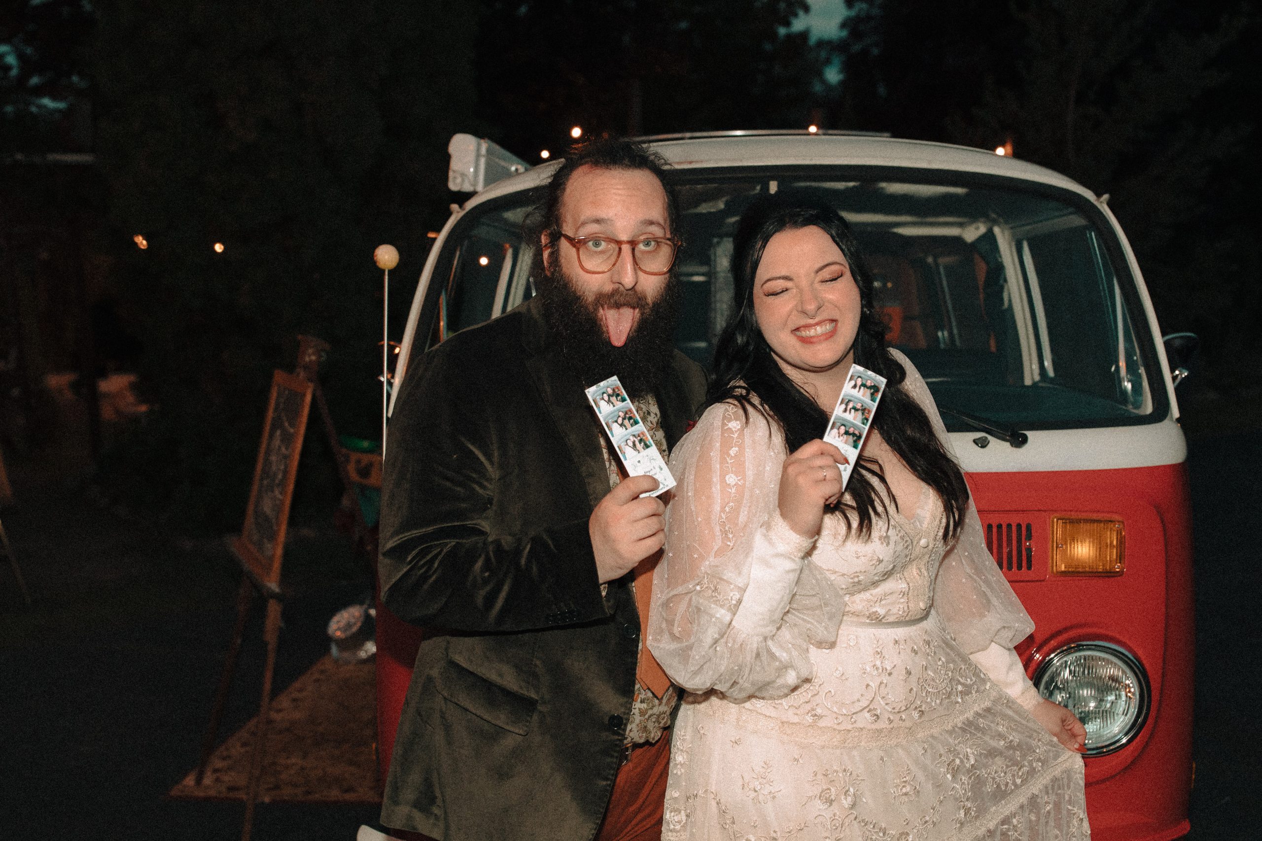 fun wedding with bride and groom being silly holding onto photo strips in front of vw photobooth bus