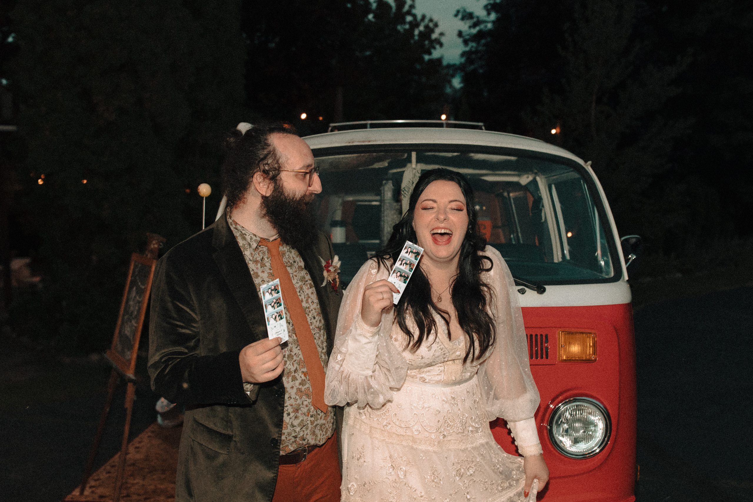 fun wedding with bride and groom being silly holding onto photo strips in front of vw photobooth bus