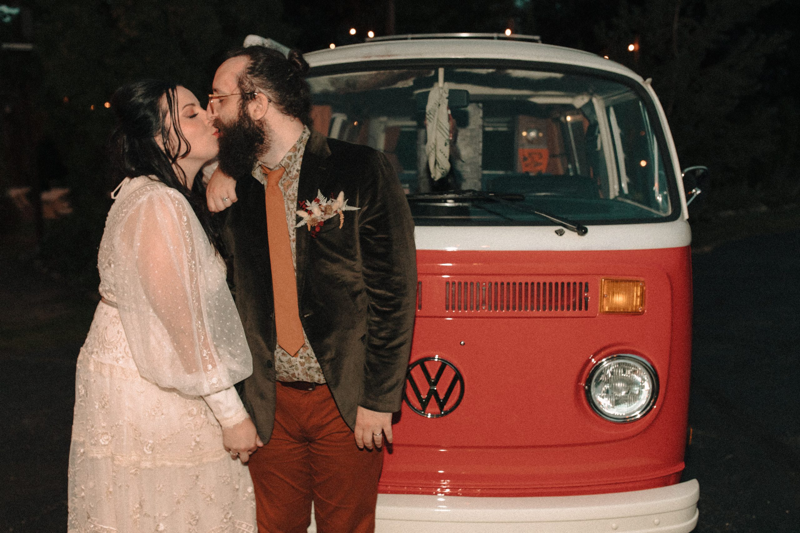 retro bride and groom kissing in front of a red Volkswagen bus