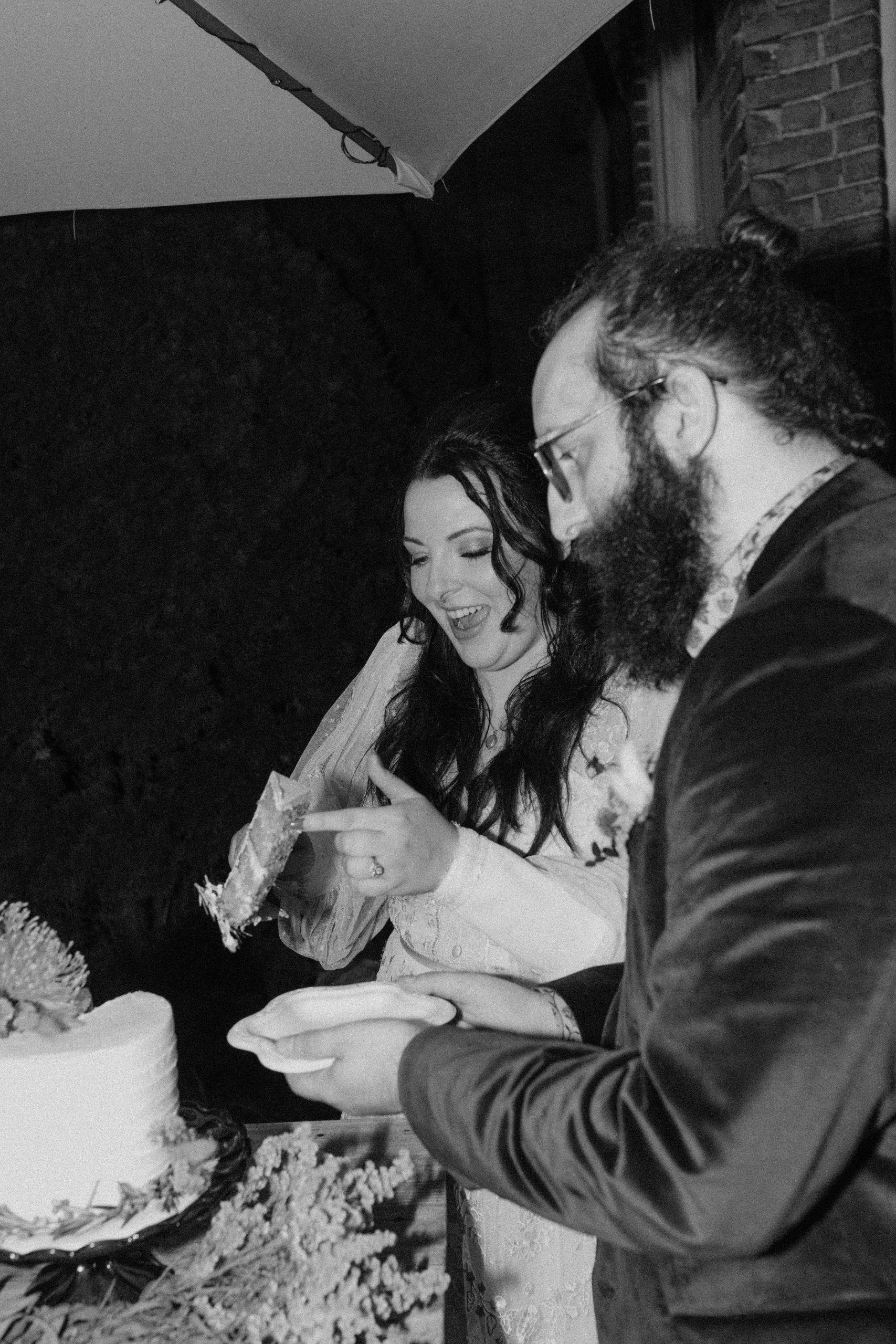 Black and white photo of bride and groom cutting cake