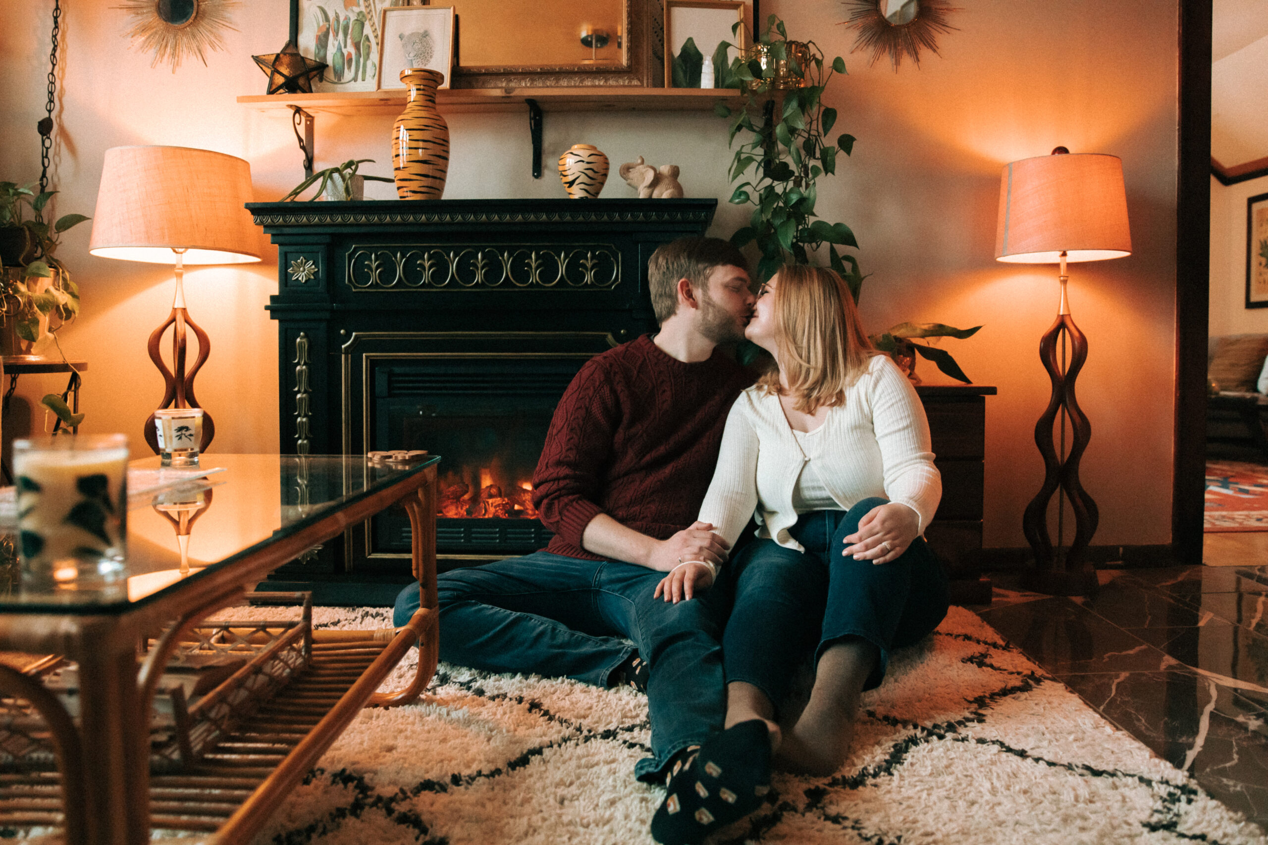Couple kissing in front of a fireplace for their engagement pictures at a milwaukee airbnb